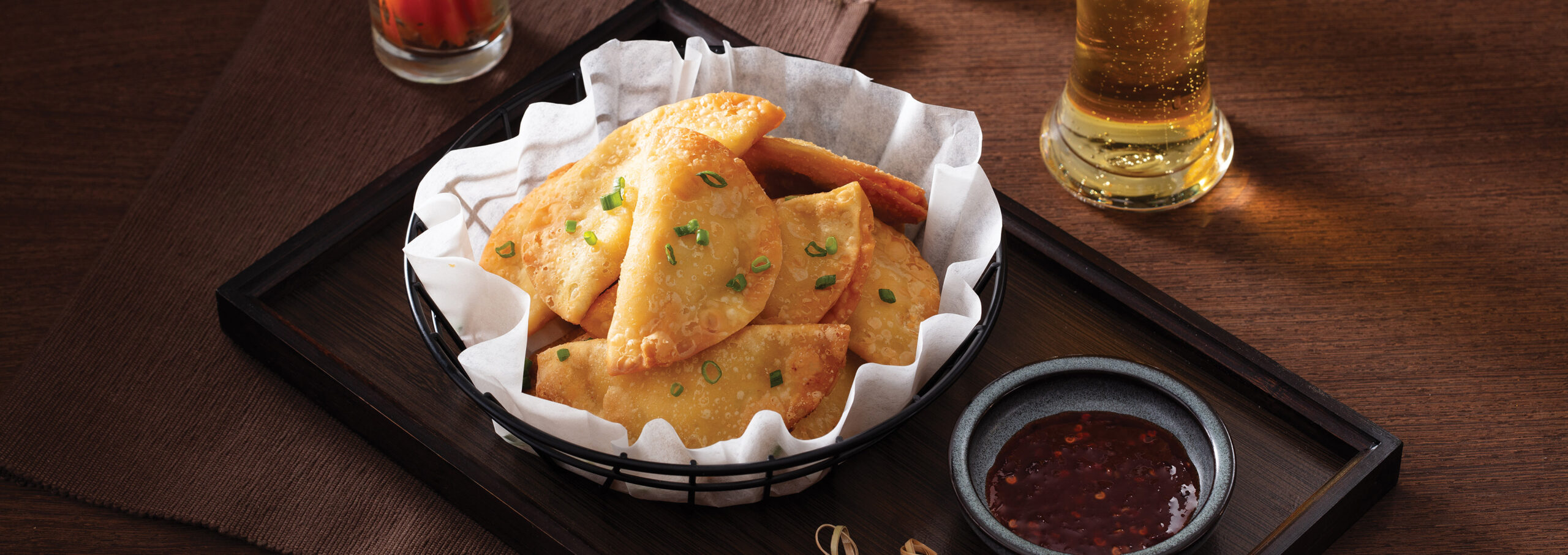 bowl of crab Rangoons with glass of beer and dipping sauce